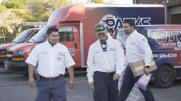 Parks technicians smiling in front of a Parks service van