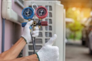 Technician inspecting an air conditioner and holding a thumbs up sign