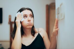 Woman adjusting the thermostat because AC isn't fully cooling