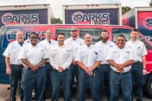 Parks technicians standing in front of service vehicles and smiling