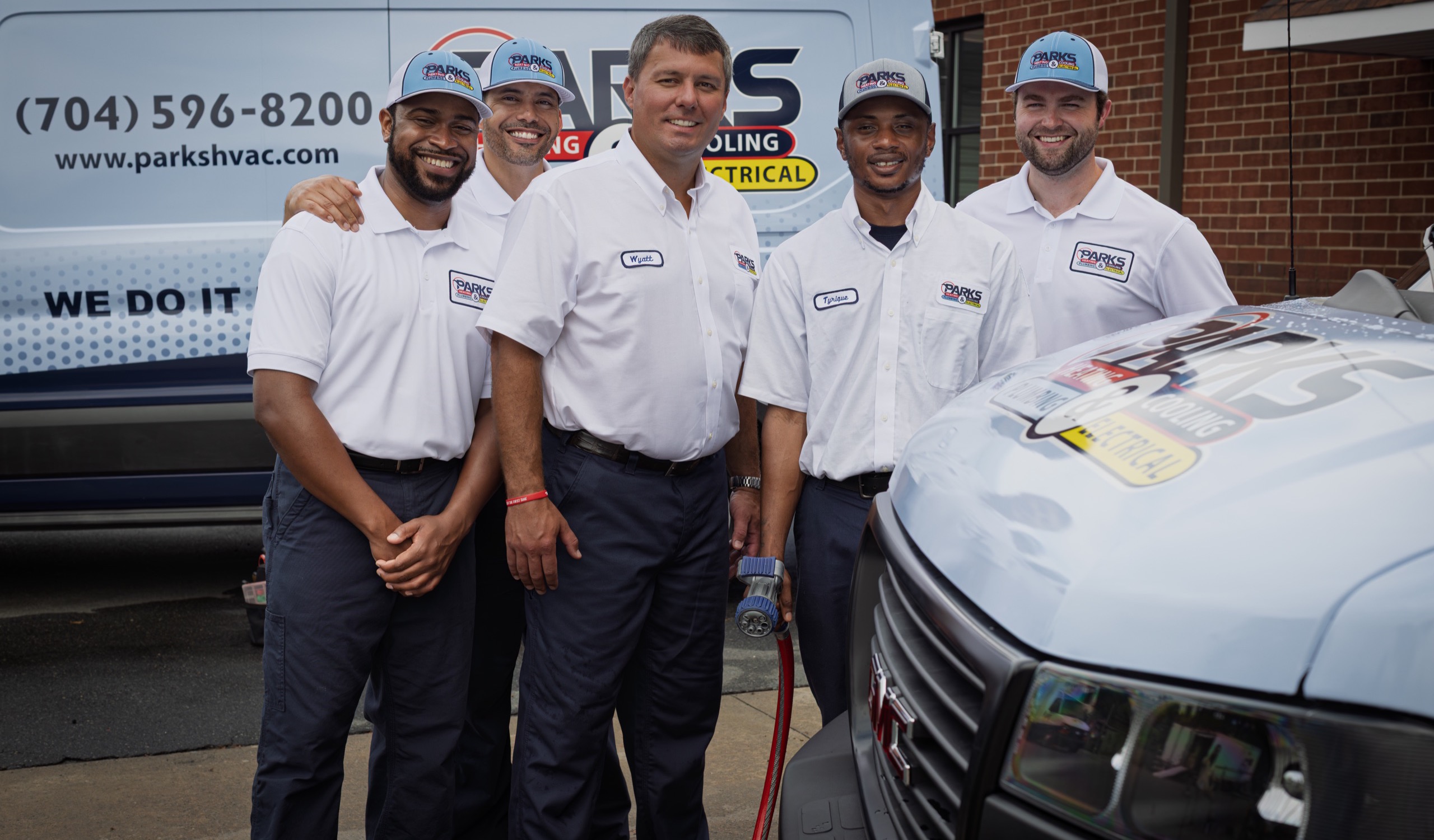 Parks HVAC team standing in front of branded service vehicles